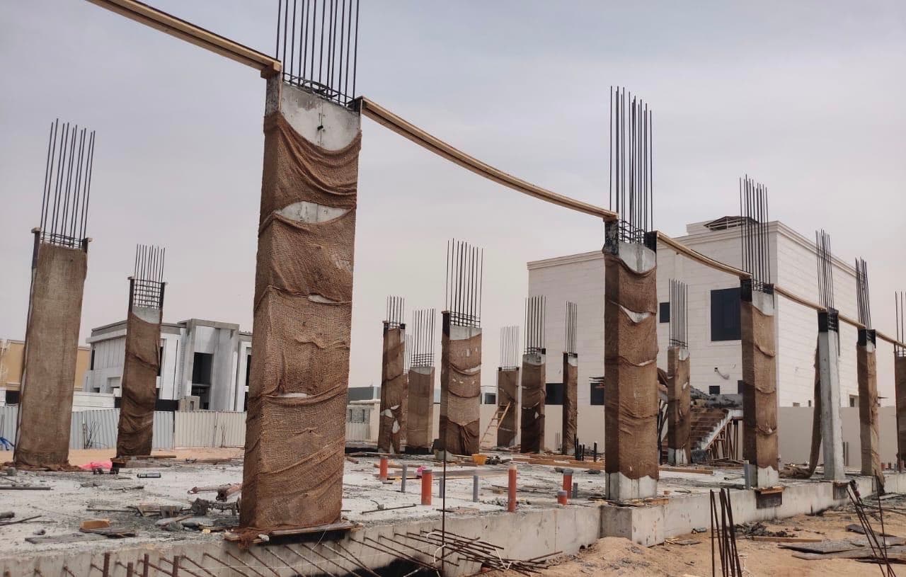 Concrete columns wrapped for curing at a villa site